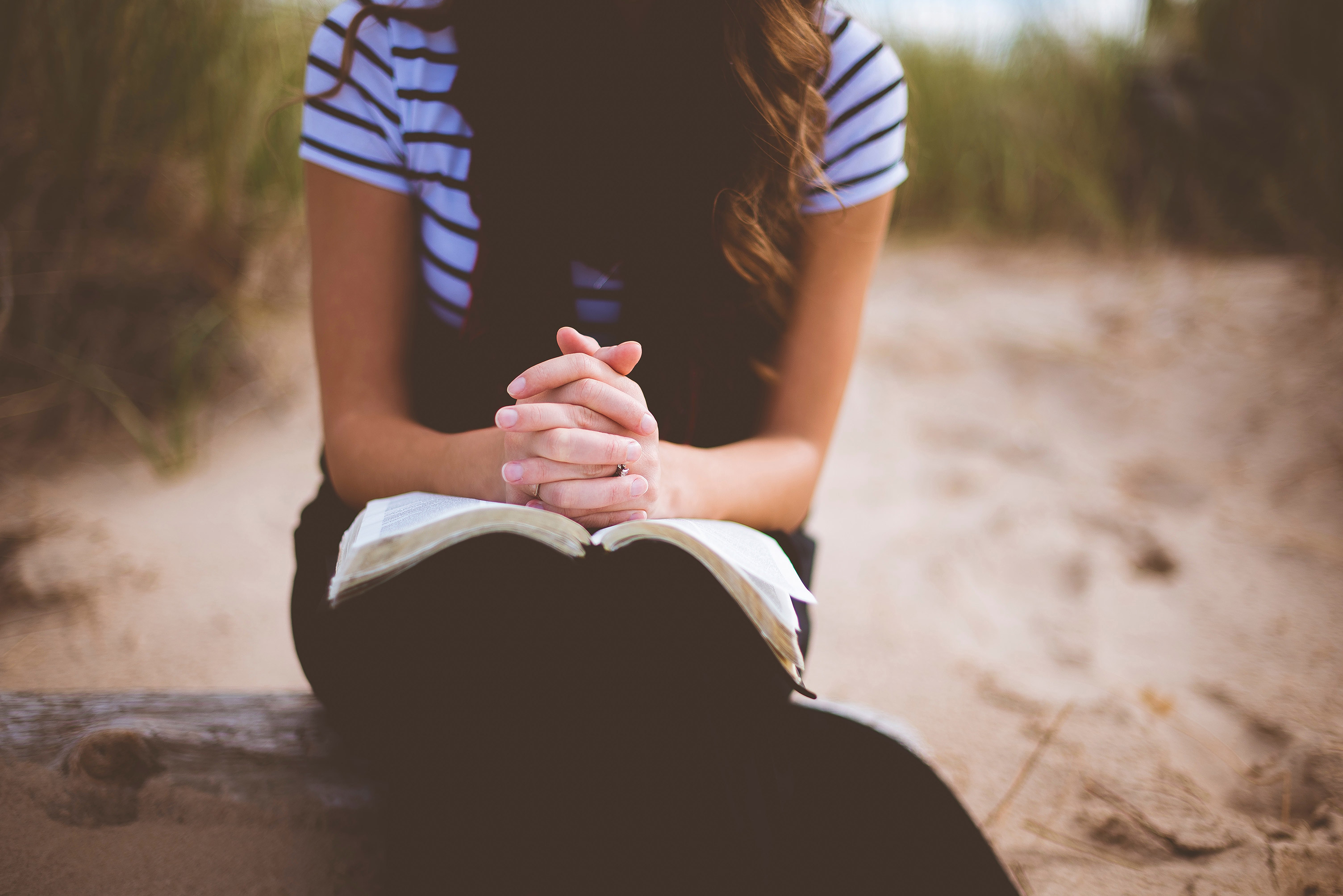 Photo of young woman praying with hands clasped together